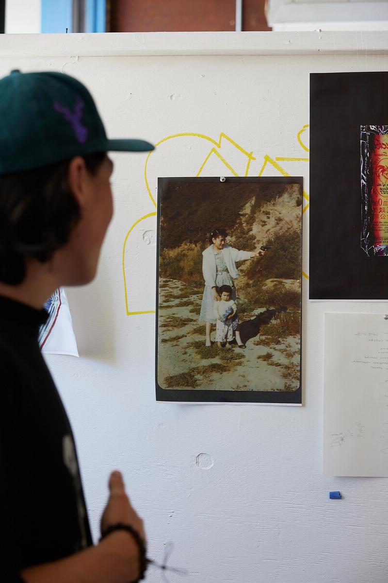 an undergraduate student in a baseball cap looks at a photograph on a wall in an art studio