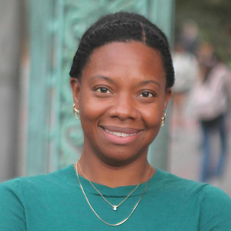 身穿蓝绿色衬衫的非裔美国女性对着镜头微笑
