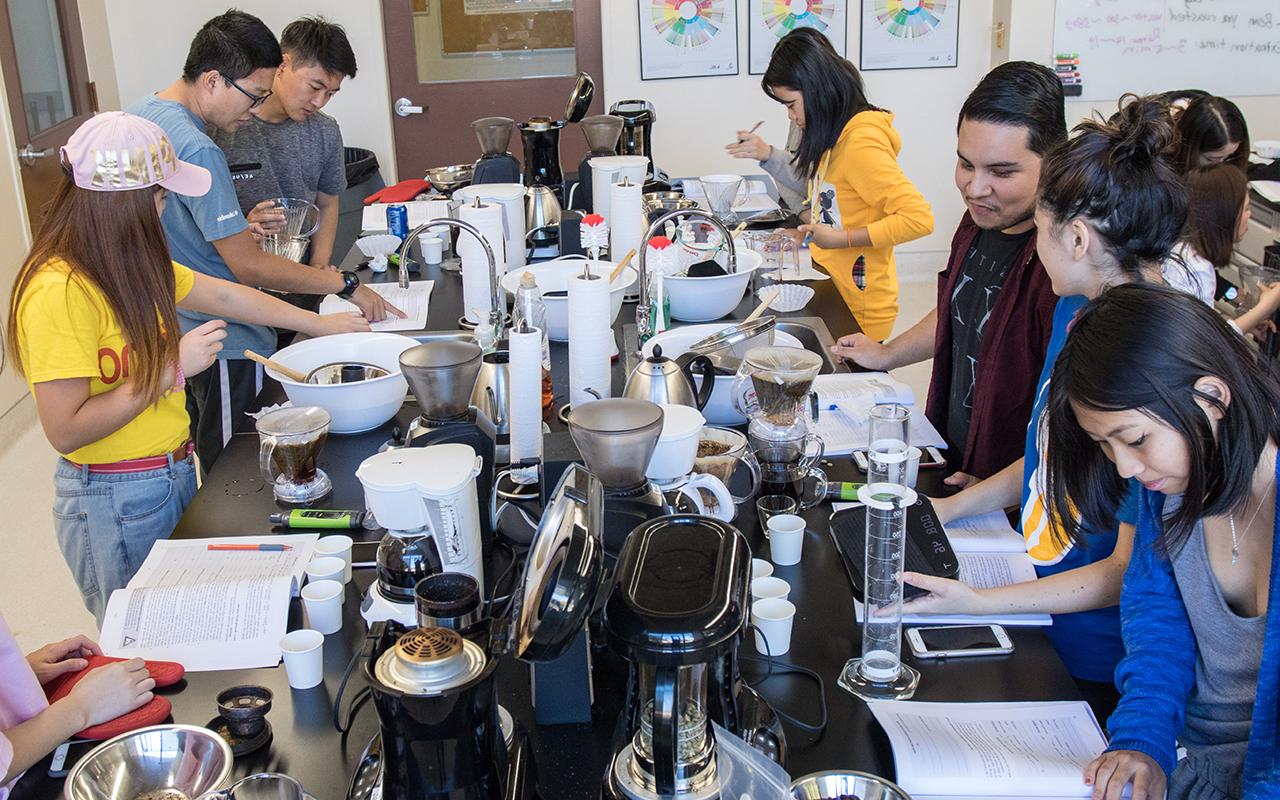 学生们围着摆满咖啡制作设备的桌子工作