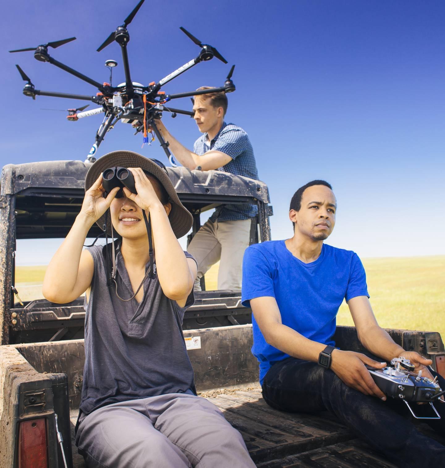 Student researchers on the back of a truck working with a drone