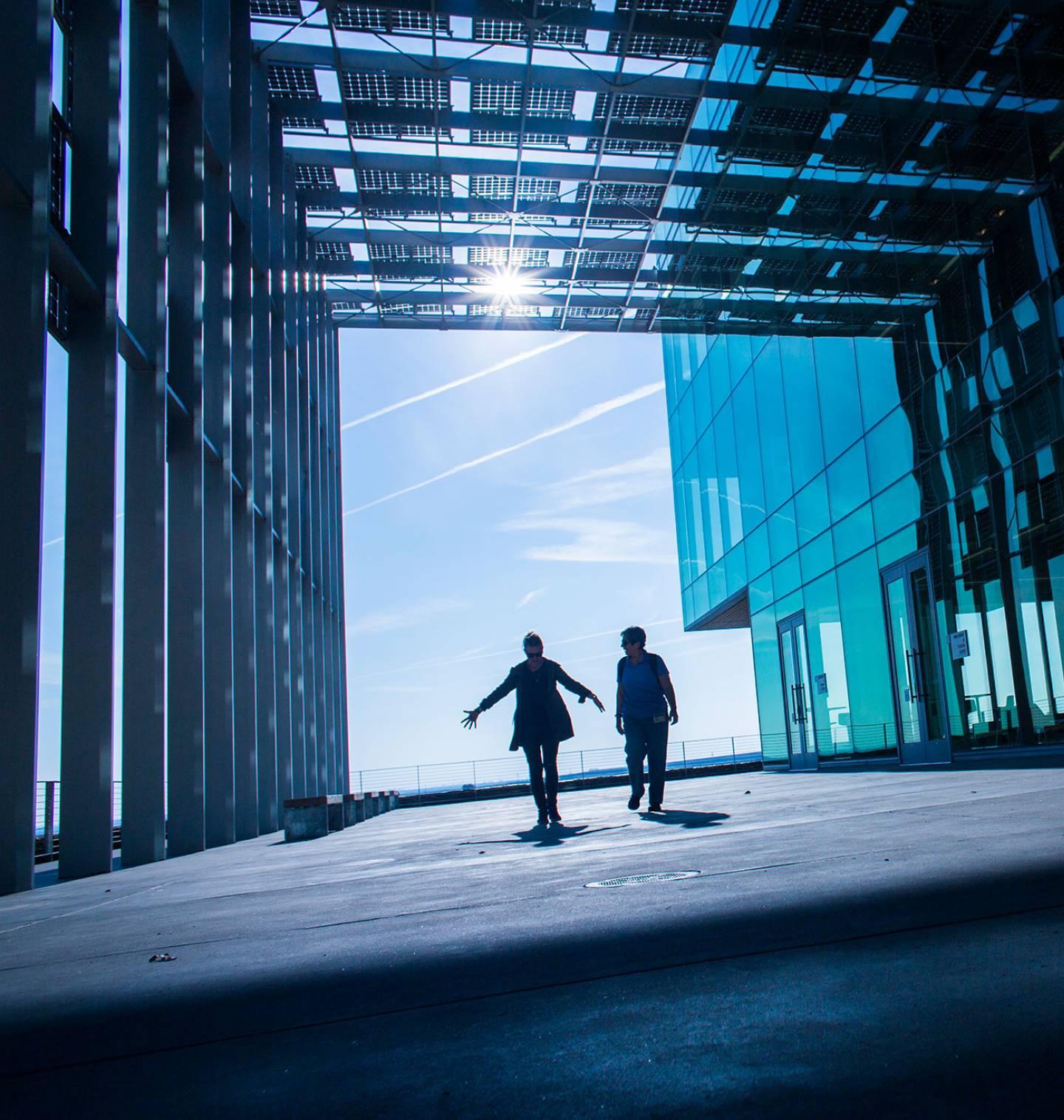 Two people walking through large hallway made of solar panels