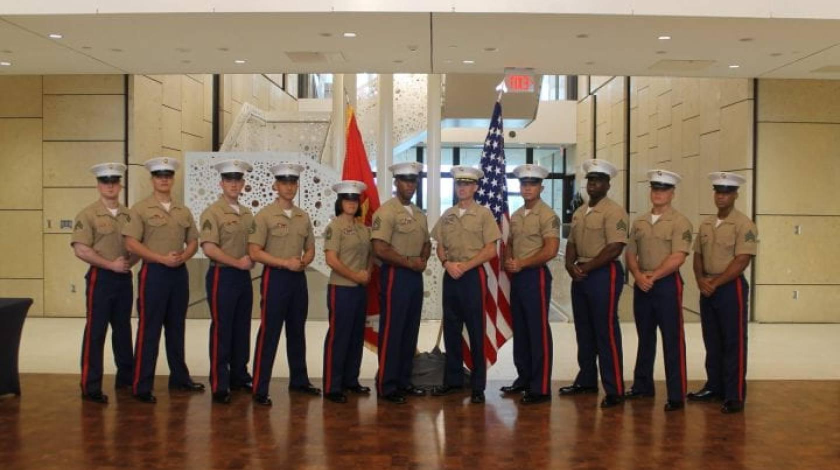 United States Marine Corps veteran and UCI sociology alumnus Andrew Truong ’23 (fourth from right), 与战友合影, 穿着制服，在国旗前悠闲地摆姿势.