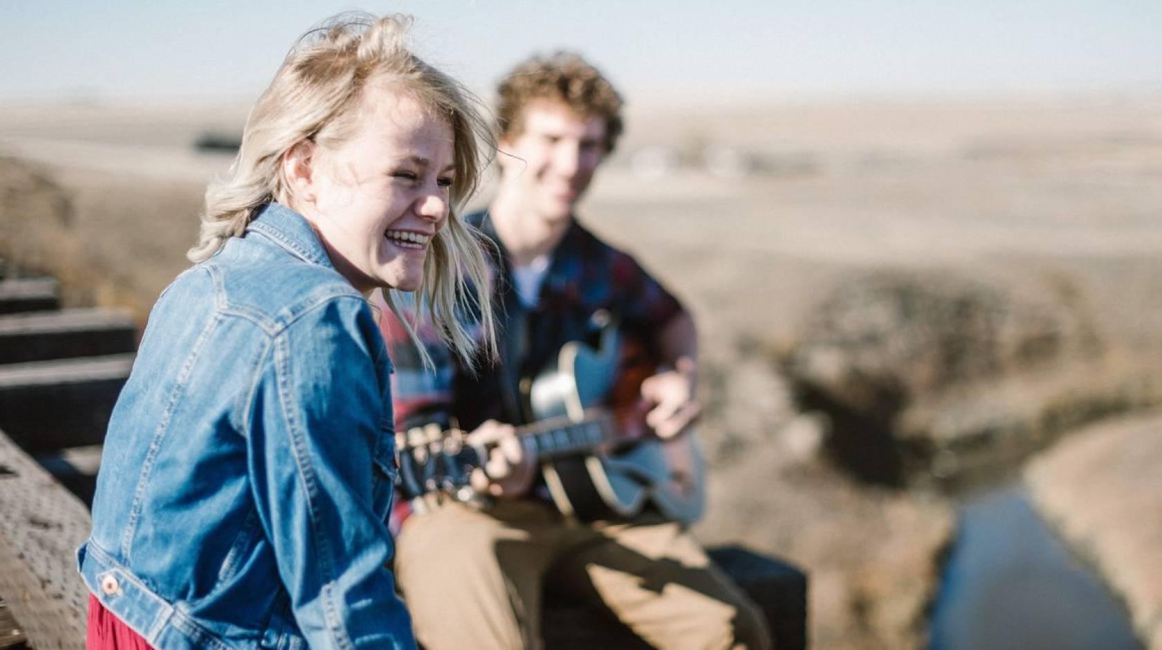 一个快乐的女人微笑着听一个男人弹吉他