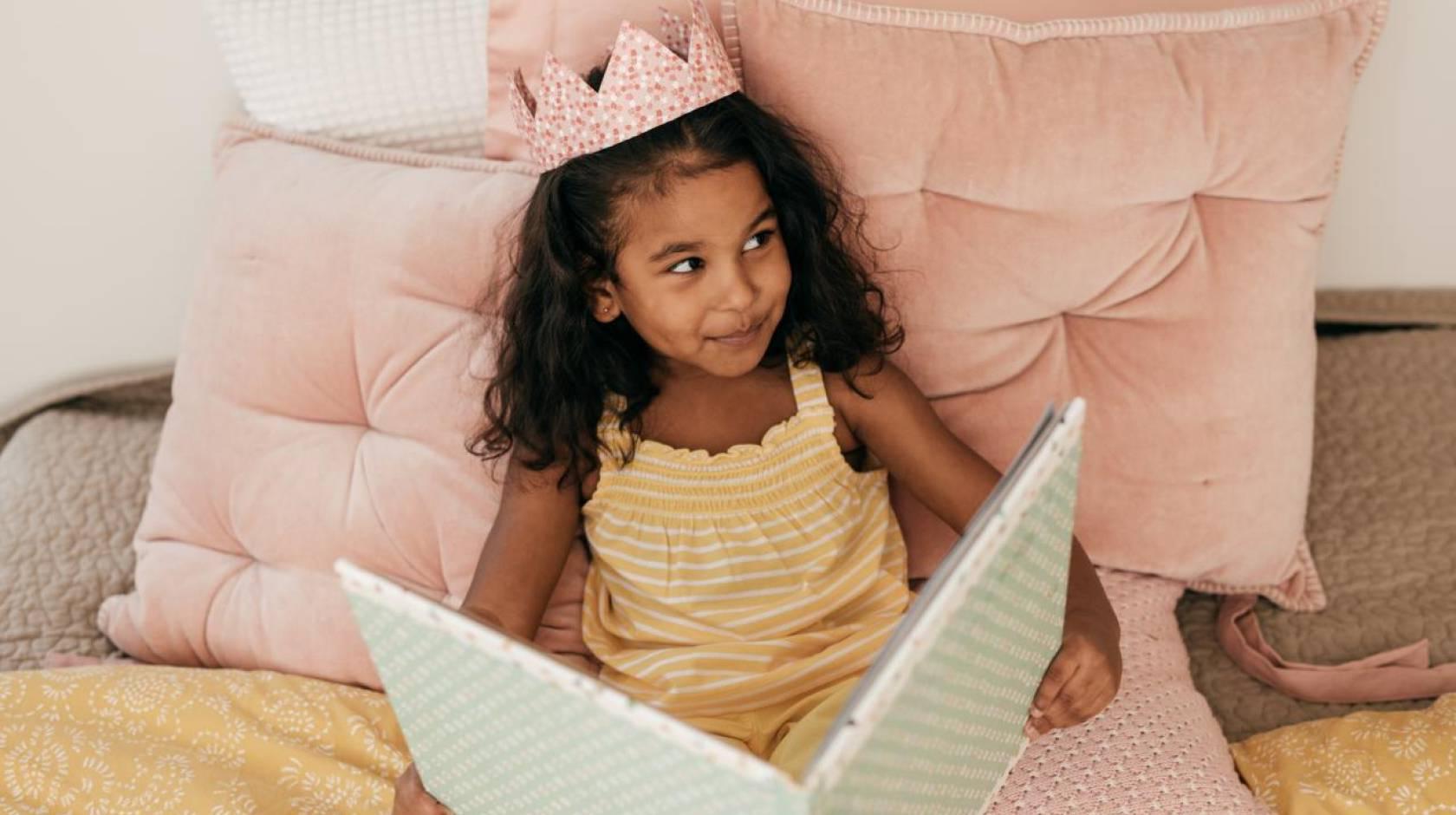 一个年轻的南亚女孩戴着皇冠，微笑着看书