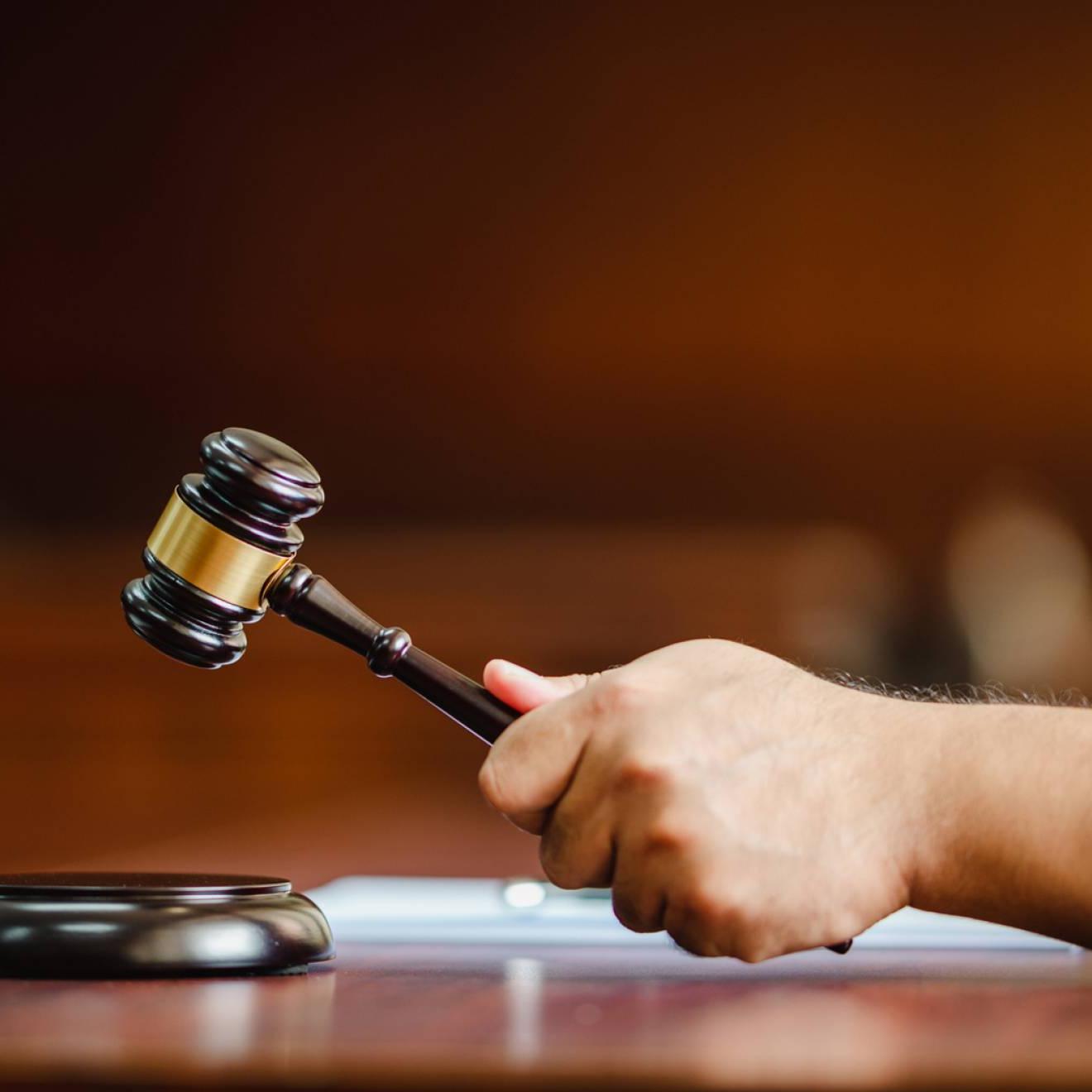一名女法官手持木槌在法庭室内的木桌上的特写