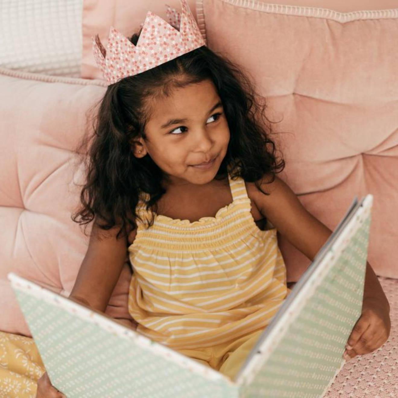 一个年轻的南亚女孩戴着皇冠，微笑着看书