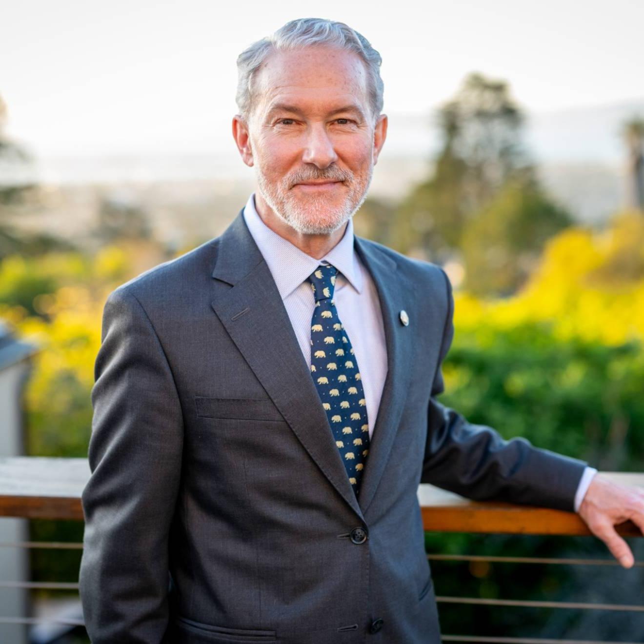 Rich Lyons, 一个白头发白胡子的白人, smiling in a suit with a Berkeley bears tie, on campus