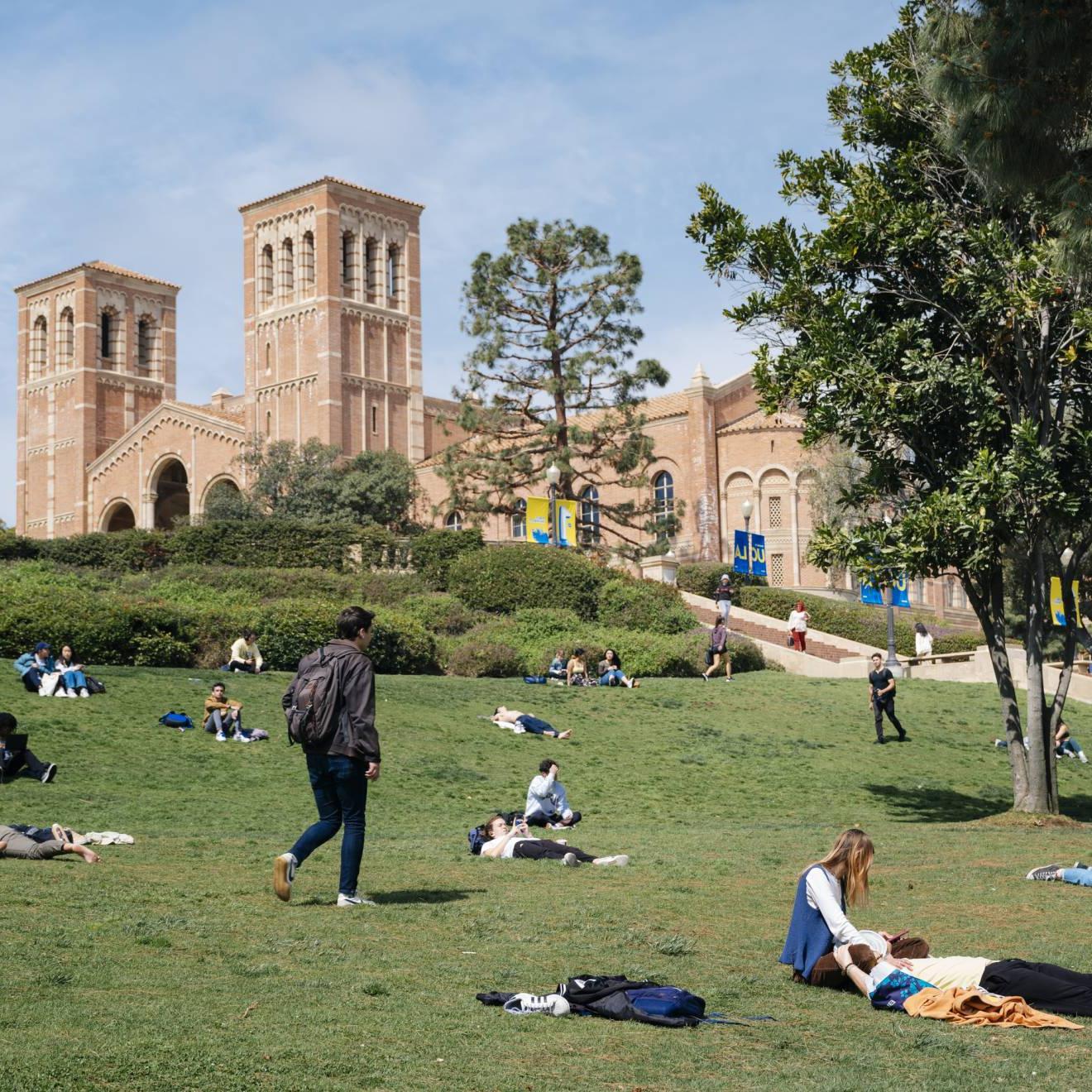Students lounge and walk across the green on a sunny day at the UCLA campus; Royce Hall in the background