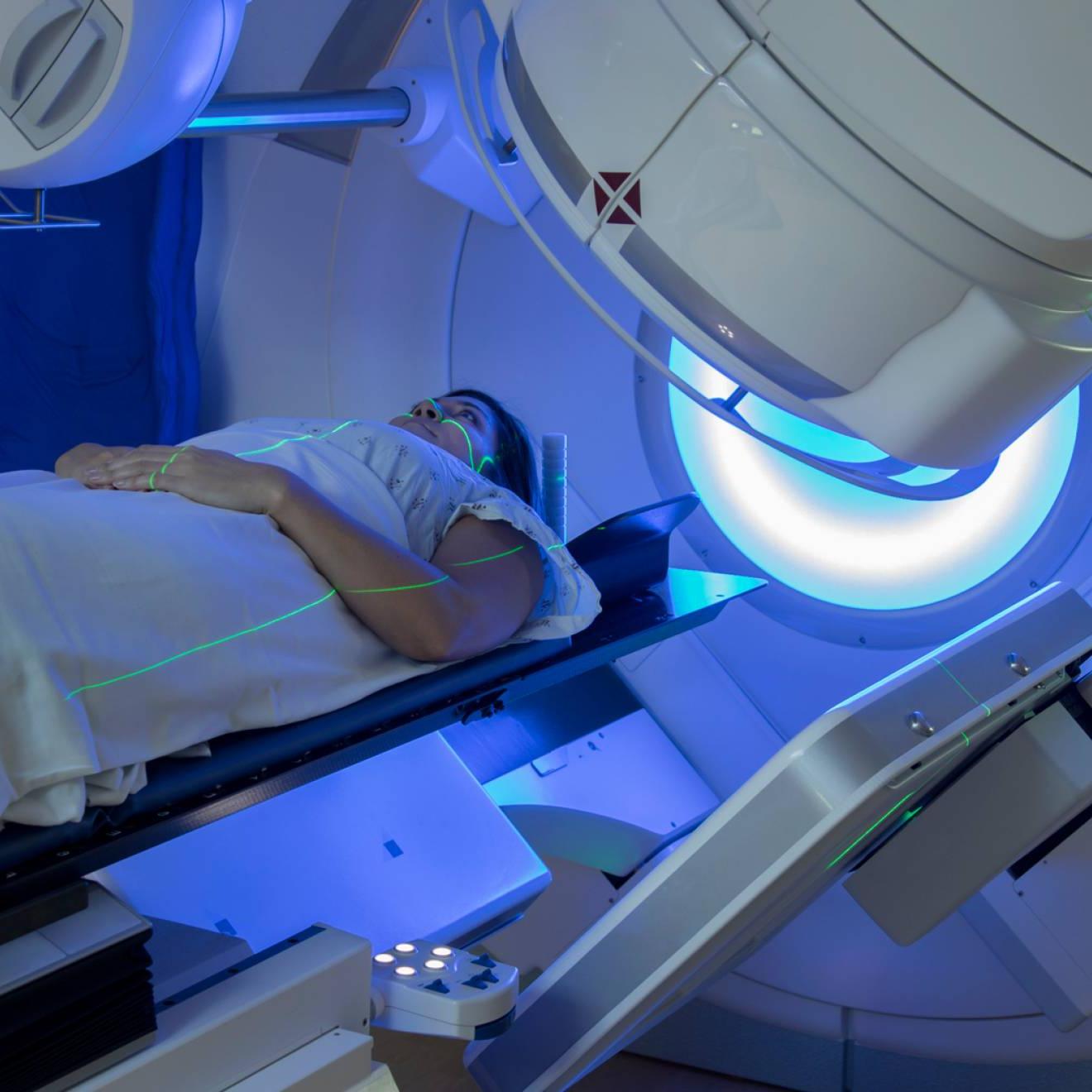 一名妇女在一台机器下接受乳腺癌放射治疗，她的脸和身体上有绿色的光线